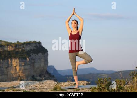 Ritratto a corpo pieno di una donna asiatica che pratica yoga posa in montagna Foto Stock