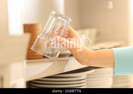 Primo piano di una mano donna che cattura un bicchiere in cucina Foto Stock