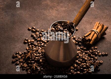 Chicchi di caffè arrosto, spezie e turk (cezve). Caffè turco piccante con cannella e composizione di anice. Foto Stock