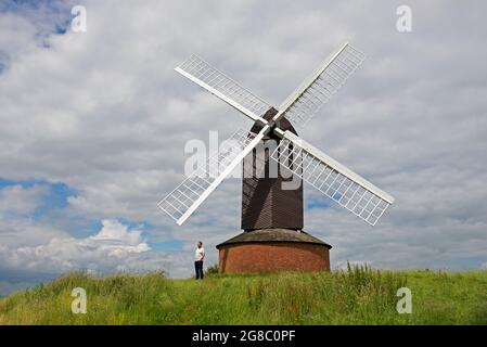 Uomo di mezza età che si trova accanto al mulino a vento di Brill del XVII secolo, Buckinghamshire, Inghilterra Regno Unito Foto Stock