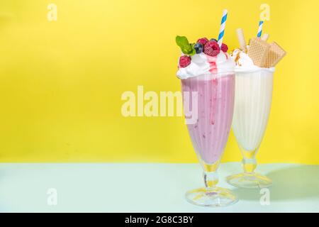 Bevande rinfrescanti estive, frullati, frullati pazzi con gelato, frutti di bosco, vaniglia, cioccolato. Su uno sfondo giallo blu brillante Foto Stock