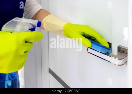Pulizia delle maniglie delle porte con un antisettico durante un'epidemia virale. Il concetto di pulizia e disinfezione. Foto Stock