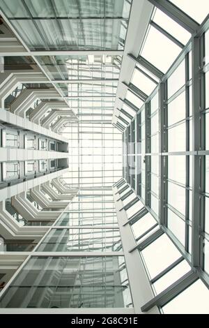 Vista ad angolo basso di un alto edificio moderno con grandi finestre e soffitto in vetro Foto Stock