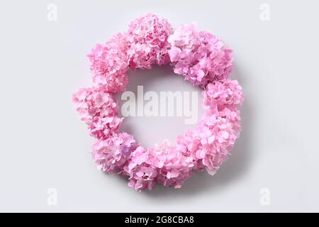 Rosa idrangea fiori come corona su sfondo grigio con spazio copia. Vista dall'alto. Biglietto d'auguri. Foto Stock