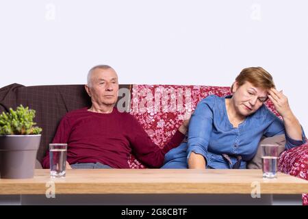 Gli adulti sono seduti sul divano vicino al tavolo con bicchieri d'acqua perché sono stanchi. Foto Stock