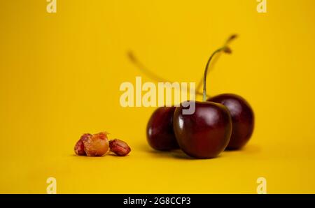 ciliegie mature con pit su sfondo giallo. Foto Stock