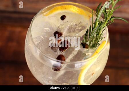 Gin e tonico con fette di limone siciliano e semi di ginepro. Foto Stock