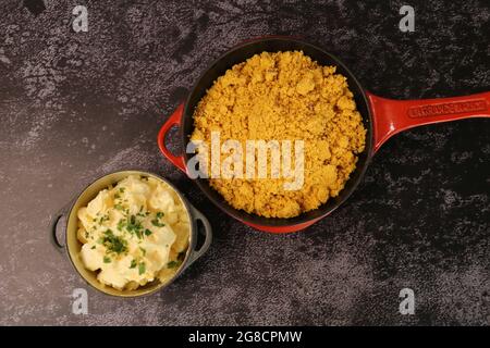 Pentola di ferro rossa con Farofa. Cucina tradizionale brasiliana. Su sfondo scuro. Foto Stock