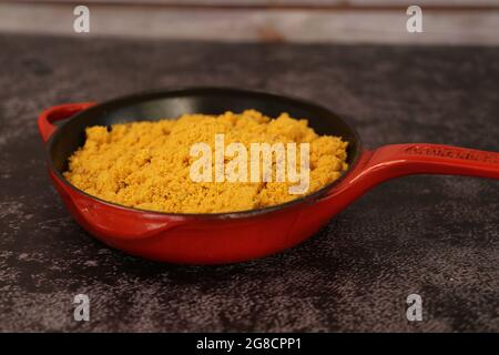 Pentola di ferro rossa con Farofa. Cucina tradizionale brasiliana. Su sfondo scuro. Foto Stock