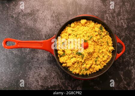 Pentola di ferro rossa con Farofa. Cucina tradizionale brasiliana. Su sfondo scuro. Foto Stock