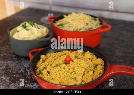 Pentola di ferro rossa con Farofa. Cucina tradizionale brasiliana. Su sfondo scuro. Foto Stock