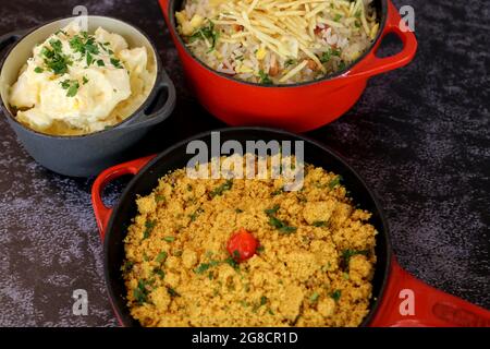 Pentola di ferro rossa con Farofa. Cucina tradizionale brasiliana. Su sfondo scuro. Foto Stock