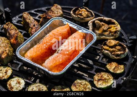 carne di vitello, salmone e zucchine su griglia da giardino con carbone Foto Stock