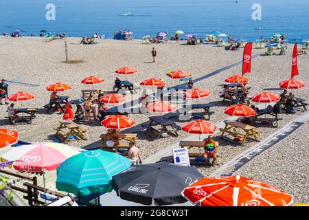 Birra, East Devon; 19 luglio 2021. Regno Unito Meteo: I vacanzieri godono del sole glorioso rilassarsi sulla spiaggia e rinfrescarsi nel mare blu presso il grazioso villaggio di pescatori e di mare di Beer, East Devon. Credit: Celia McMahon/Alamy Live News Foto Stock