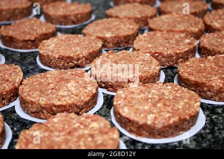 molti hamburger crudi fuori dal ristorante. Avvio della preparazione degli hamburger Foto Stock