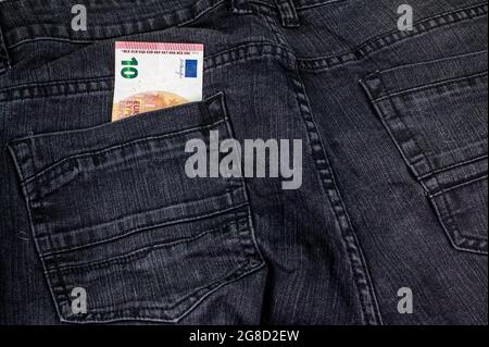 10 euro che escono dalla tasca di jeans neri Foto Stock