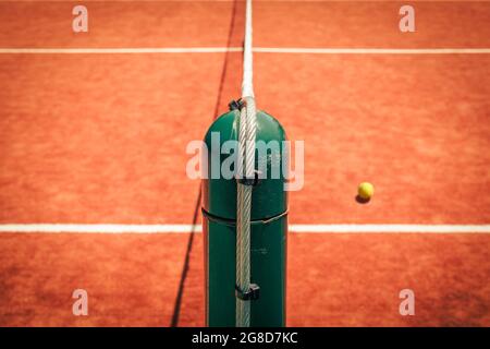 Palo da tennis in acciaio e palla da tennis da alta angolazione. Campo da tennis paletto divisorio a metà. Concetto sportivo individuale competitivo. Foto Stock