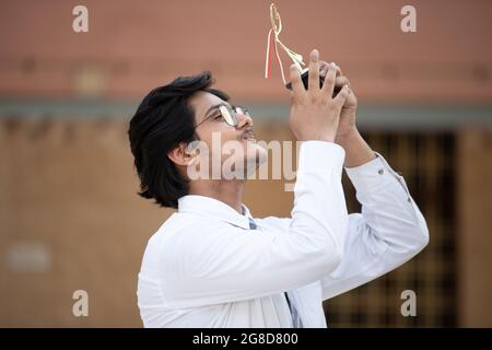 Ritratto di uno studente felice con il Premio in mano, celebrando il successo Foto Stock