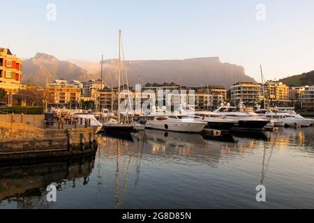 Costose barche di lusso nel porto turistico al V&A Waterfront, con Table Mountain in background, nel tardo pomeriggio, Città del Capo Sud Africa Foto Stock