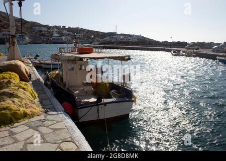 Isola di Sikinos, Grecia. Piccola barca da pesca ormeggiata in una banchina nel porto. Scena tranquilla e colorata. Cielo blu e spazio copia. Foto Stock