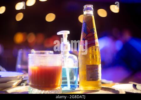 famosa bottiglia kingfisher di marca di birra indiana con bolla che esce con luci di sfondo fuori fuoco con palline bokeh che la mostrano inserita in un bar club Foto Stock