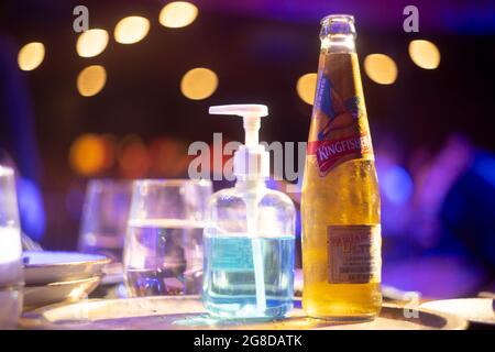 famosa bottiglia kingfisher di marca di birra indiana con bolla che esce con luci di sfondo fuori fuoco con palline bokeh che la mostrano inserita in un bar club Foto Stock