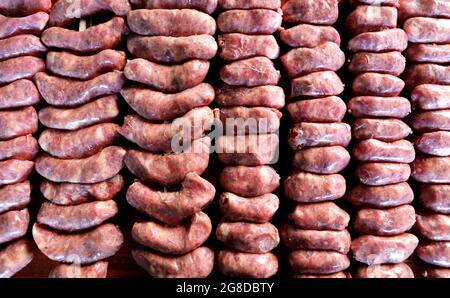 Un sacco di spiedini di salsiccia cruda. Pronti per arrostire sul barbecue. Su una tavola di legno sullo sfondo. Foto Stock