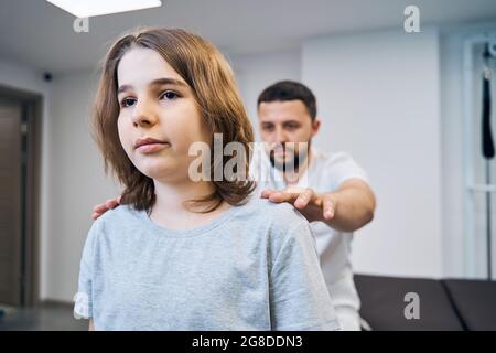 Il medico fisioterapista esamina il collo della ragazza, la colonna vertebrale nel ritratto closeup del centro medico. Chiropratico Foto Stock