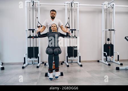 Il kinesiologist aiuta la giovane donna che fa gli esercizi per rinforzare i muscoli posteriori. Trattamento di pazienti di sesso femminile Foto Stock