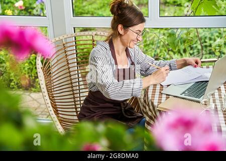 Donna che compila documenti di lavoro a casa. Lavoro domestico e remoto Foto Stock