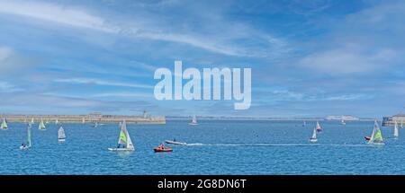 Attività sportive estive in pieno svolgimento nel porto di Dun Laoghaire a Dublino, Irlanda. In lontananza un traghetto Stena si avvicina al porto di Dublino. Foto Stock