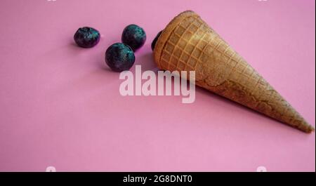 cono di waffle con gelato e mirtilli su sfondo blu. Gelato isolato primo piano Foto Stock