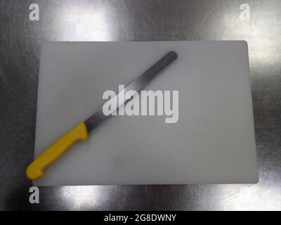 Colpo di testa di un coltello di pane lungo su una tavola bianca Foto Stock