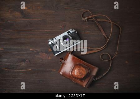 Fotocamera retrò e fondina su sfondo tavolo in legno. Disposizione piatta. Foto Stock