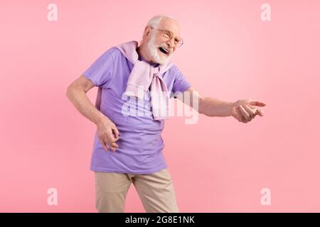 Ritratto fotografico di pensionato divertente fingendo di suonare la chitarra sul palco isolato su sfondo di colore rosa pastello Foto Stock