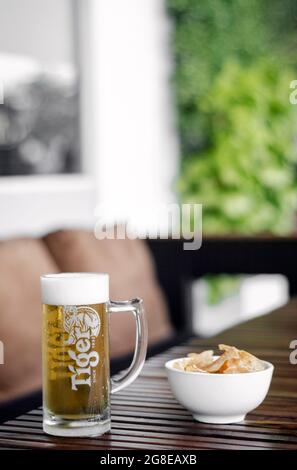 Bicchiere di birra alla spina Tigre e patatine Taro sul tavolo esterno della terrazza del bar a singapore Foto Stock