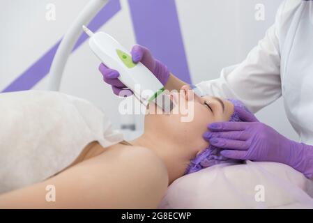 Salone di bellezza. Il cosmetologo effettua una procedura di peeling dell'acqua per il cliente. Vista laterale. Il concetto di cura professionale della pelle. Foto Stock