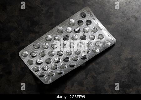 Confezione argentata grinzito vuota da pillole sul tavolo primo piano. Foto Stock