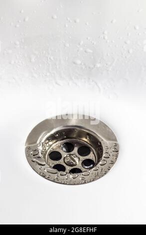 Primo piano di un foro di scarico in un lavello in ceramica bianca. Foto Stock