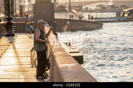 Pescatore di città che dispone la sua canna da pesca con una rete in mattina presto, 5, sul terrapieno Lt Shmidta, fiume Neva, San Pietroburgo, Russia Foto Stock