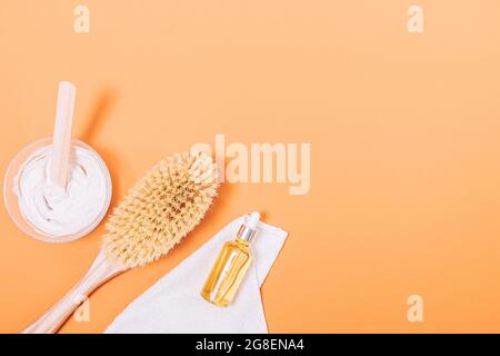 Vista dall'alto della spazzola per il corpo accanto alla maschera di argilla, al tovagliolo e alla bottiglia di olio organico sul tavolo con spazio per la copia. Foto Stock