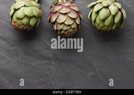 Carciofi freschi su fondo di pietra grigio scuro Foto Stock