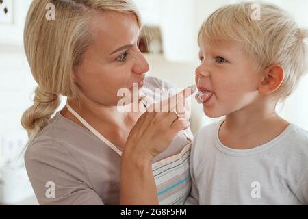 Mamma con il figlio cucina torta vacanza in cucina. Stile di vita casual Foto Stock