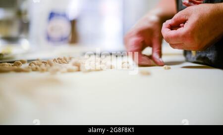 Donna caucasica adulta che prepara pisarei, pasta tradizionale italiana estrusa di Piacenza Foto Stock