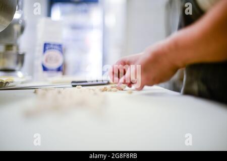 Donna caucasica adulta che prepara pisarei, pasta tradizionale italiana estrusa di Piacenza Foto Stock