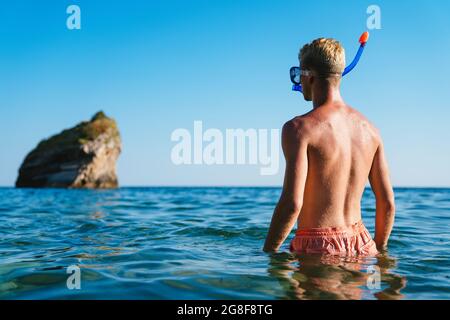 Uomo felice con maschera per il snorkeling sulla spiaggia in vacanza estiva Foto Stock