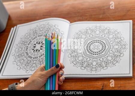 una manciata di matite colorate e un libro di mandala da colorare Foto Stock