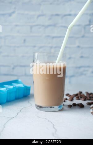 ghiaccio il caffè in un bicchiere alto con i chicchi di caffè sul tavolo Foto Stock