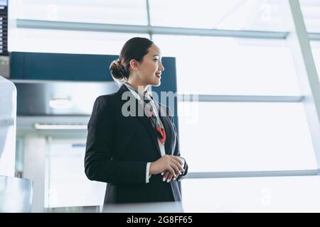 Vista laterale dell'assistente di volo al lavoro. Personale di terra in uniforme presso il terminal dell'aeroporto. Foto Stock