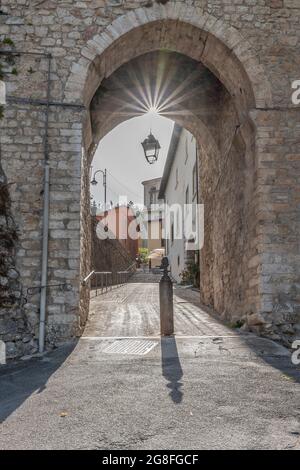 L'antica porta orientale che dà accesso al centro storico di Cascia, Italia, con i raggi del sole che filtrano dall'alto Foto Stock